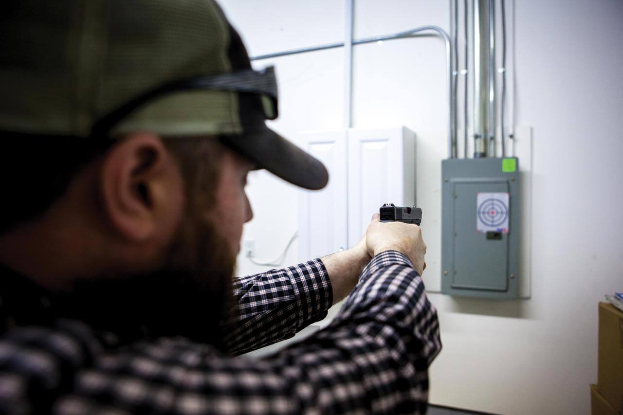 Chris Jones aims his pistol at a bullseye on the wall