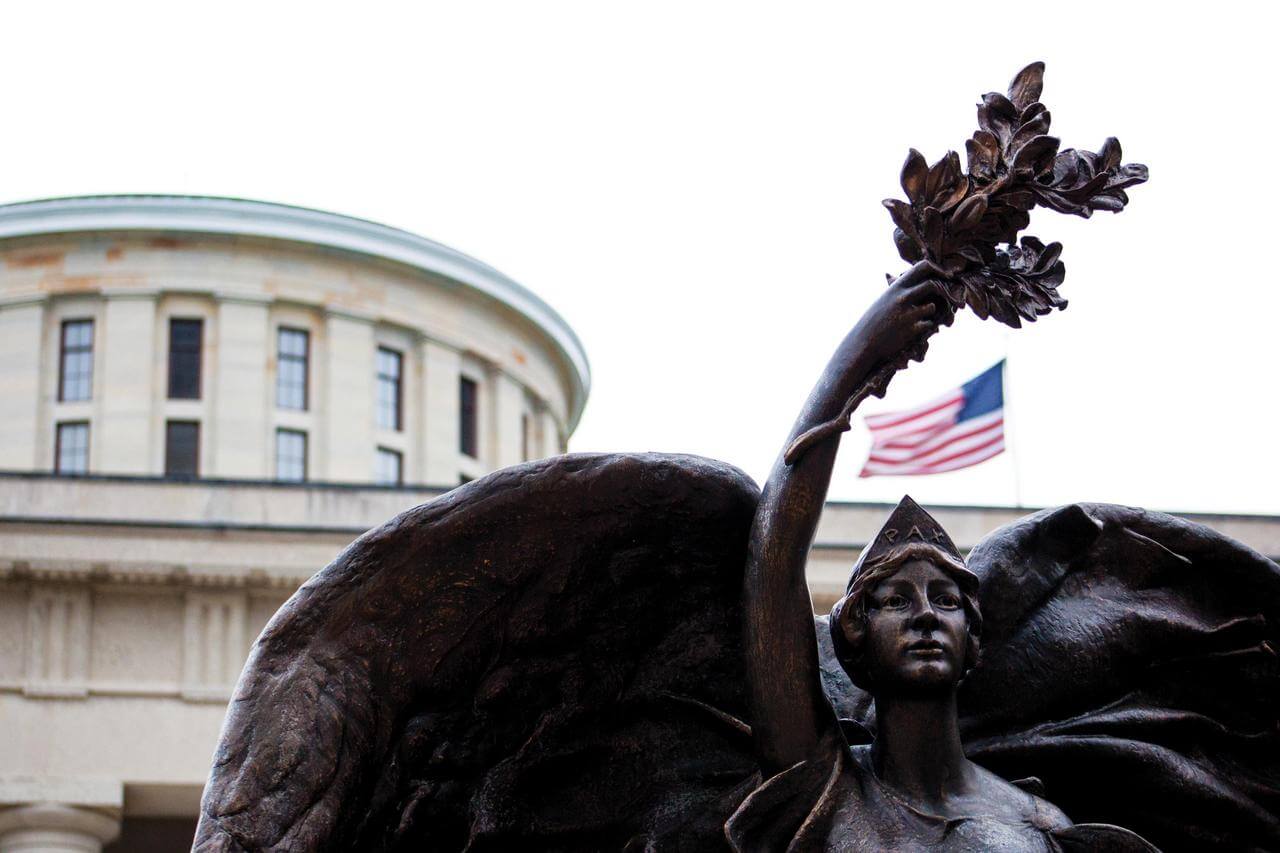A statue of a woman lifting an olive branch above her head